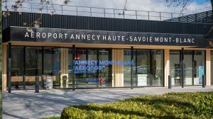 The exterior of the new terminal at Annecy Haute-Savoie Mont-Blanc airport, with a grass verge to the front and the airport name above the doors.