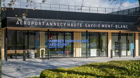 The exterior of the new terminal at Annecy Haute-Savoie Mont-Blanc airport, with a grass verge to the front and the airport name above the doors.
