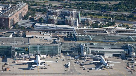 EU air connectivity “flatlined under high costs and onerous regulation” in 2025, IATA reports Aerial view of an airport with aircraft parked at gates around a large central terminal.