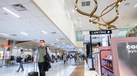 The DFW International concourse with passengers walking past a range of concessions.