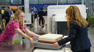 Passengers use a CT scanner at an airport security line.