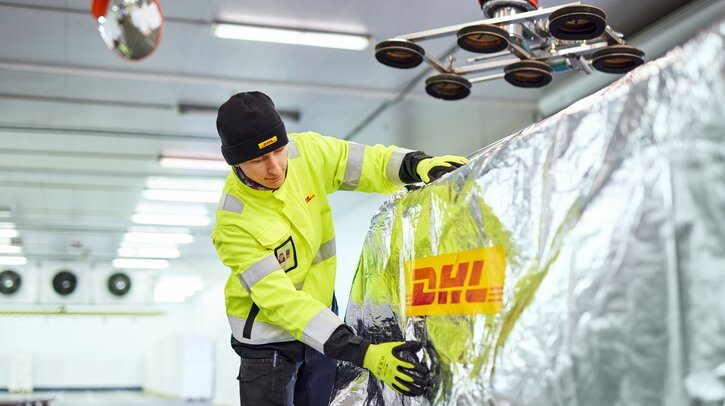 A young warehouse worker is checking pallets that have been covered for transport.