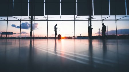 UK seeks airport security innovations in new open call Silhouette of a man standing in a quiet airport terminal with glass window behind him.